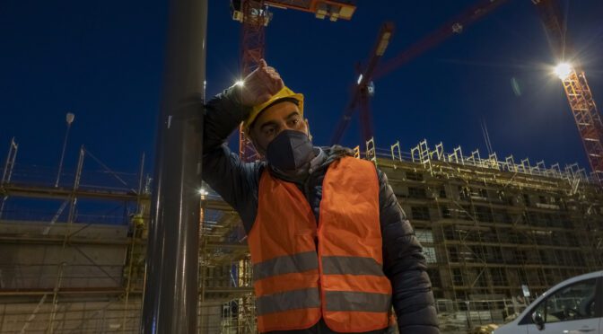 Night time, Male worker in uniform is tired and wiping his forehead